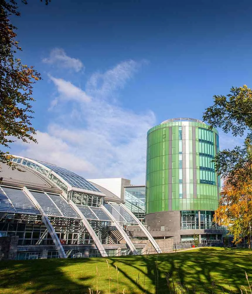 Кампус Robert Gordon University в Абердине осенью: круглый корпус в зелёном стекле и стеклянная кровля атриума над газоном